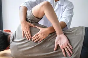 physiotherapist helping a patient with back pain