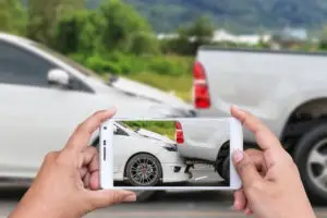 man taking picture of truck and car crash