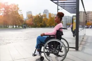 black woman in a wheelchair at a bus stop