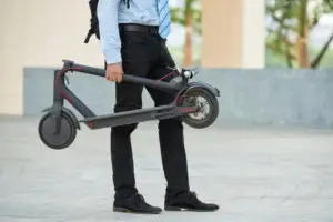 businessman holding a folded electric scooter