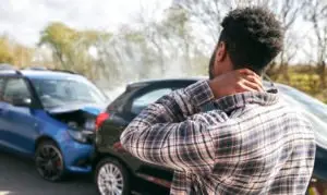 man rubbing neck after a car crash