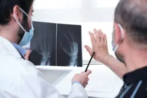 Doctor shows worker an x-ray of his finger injury.