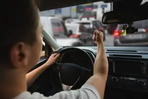 a young man making a fist while driving in heavy traffic