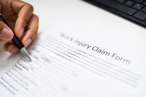 a close-up of a hand filling out a work injury claim form