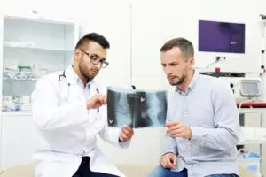 Medical professional and patient discussing the injuries present on the x-ray after a car accident.