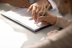 A woman signs a contract with a lawyer after a free consultation. Consultations are free with most personal injury lawyers.