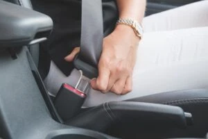 person locking their seatbelt in a car