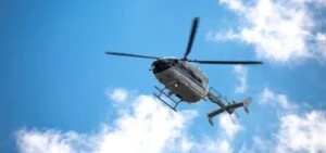 A helicopter flies in the air, and the passengers wonder what steps to take after an airplane or helicopter crash.