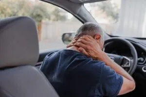 Middle-aged man grabbing his neck after being injured while driving for Grubhub