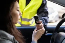 police officer administering breathalyzer test to drunk woman