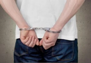 A man in handcuffs, going to jail or prison.