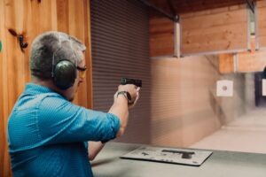 A main aiming a pistol at a gun range, wondering how much it costs to restore your gun rights.