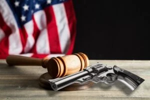Gun sitting next to a gavel with an American flag in the background to symbolize the question of whether Ohio requires gun registration.