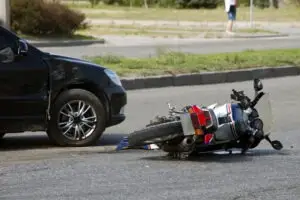 down motorcycle by black car