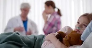 little girl hugging teddy bear in the hospital