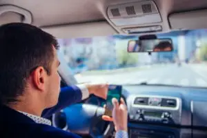 man driving while checking phone