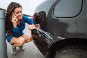 woman making a call near scratched black car