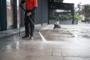 person power-washing sidewalk