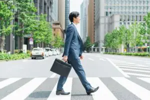 businessman in crosswalk holding a briefcase while walking through the city
