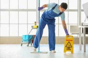 janitor placing a wet floor sign