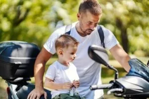 man teaching son about his motorcycle