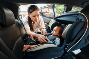 mom buckling child into a car seat