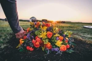 A man placing flowers on the grave of a family member who was killed in a car accident