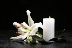 white candle and white flower in remembrance