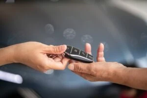 A customer receiving rental car keys from the rental car company. What happens if you crash a rental car?