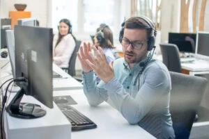 Call center worker sits at desk and uses headset to explain what an emergency exception under the TCPA is.