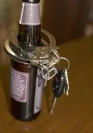 Keys and hendcuffs on the boutle of beer