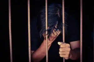 Man holding head behind prison bars