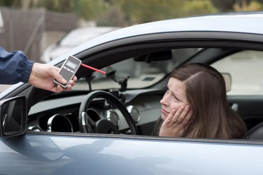 female motorist looks despondently at failed breathalyzer test