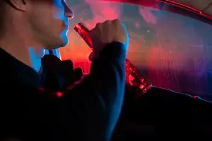 motorist drinks beer while police lights flash