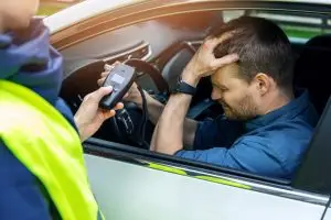 motorist holds head as officer shows him breathalyzer results