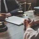 Lawyer meets with a client at his desk.