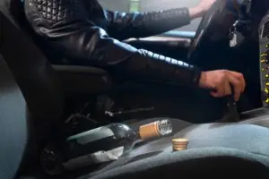 man driving next to alcohol bottle