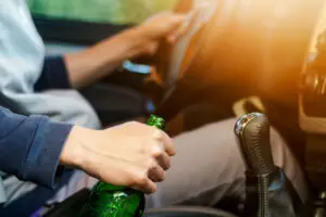 man driving with beer bottle