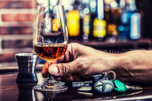 man holding a drink next to car keys