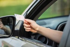 A driver shows a police officer his expired license at a traffic stop. The penalties for driving with an expired license in California include fines and jail time.