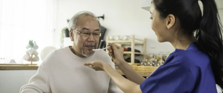 elderly man being fed by a nurse