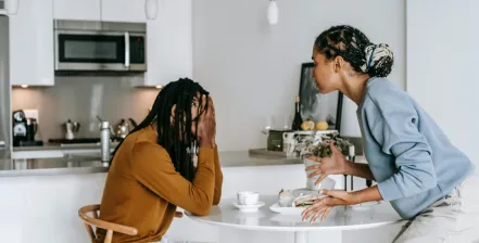 A young African American Couple argues at their kitchen table