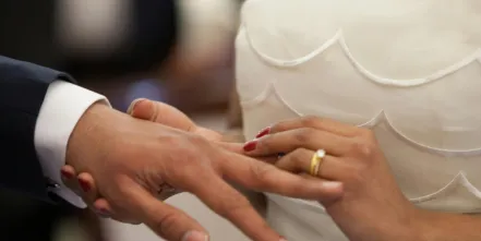 A close up a newly wedded couple's hands exchanging wedding rings