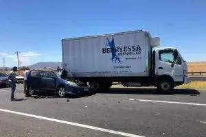A white semi-truck and a damaged blue car on the road after an accident