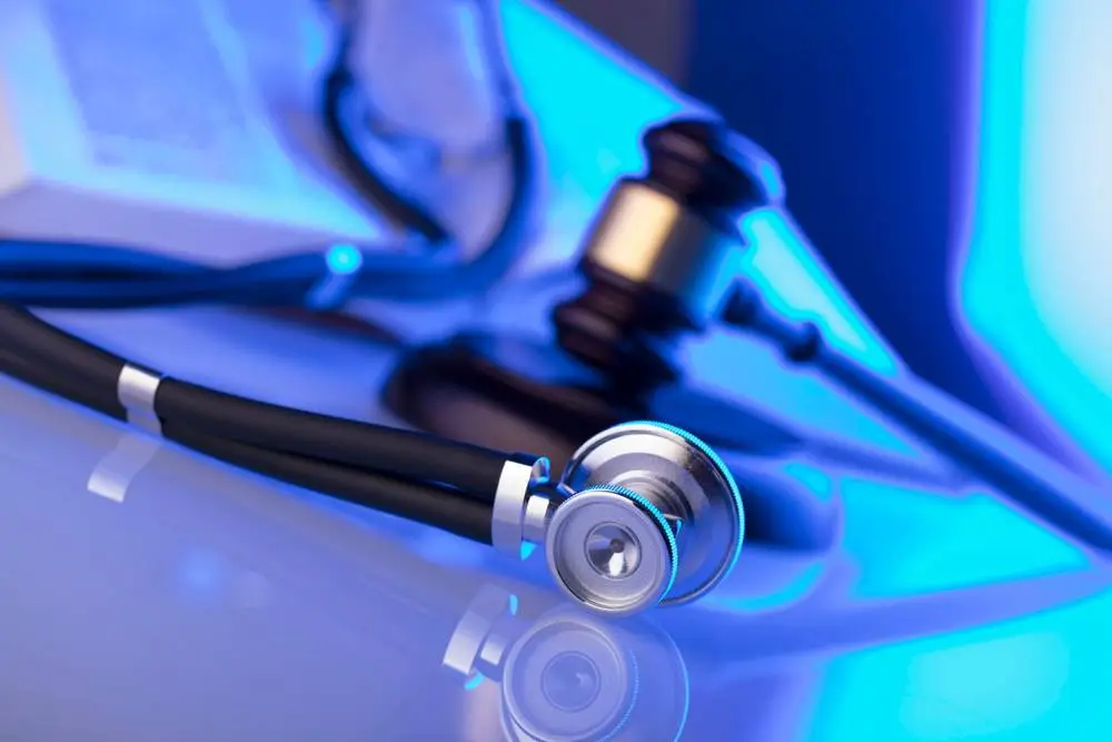 A gavel and stethoscope lay near a law book.