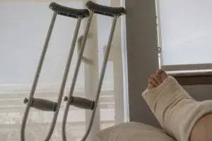 person with ankle injury in bed with crutches