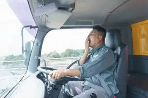 Truck driver yawns while behind the wheel
