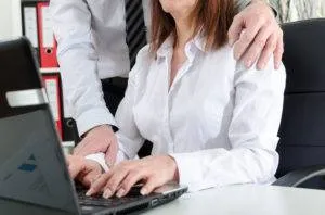 businessman touching female coworker's shoulder while at work