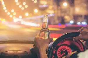 drunk driver holding beer bottle while behind the wheel