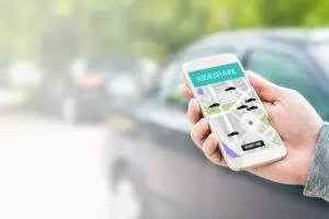 a hand holding a phone showing a ridesharing app on the side of the road